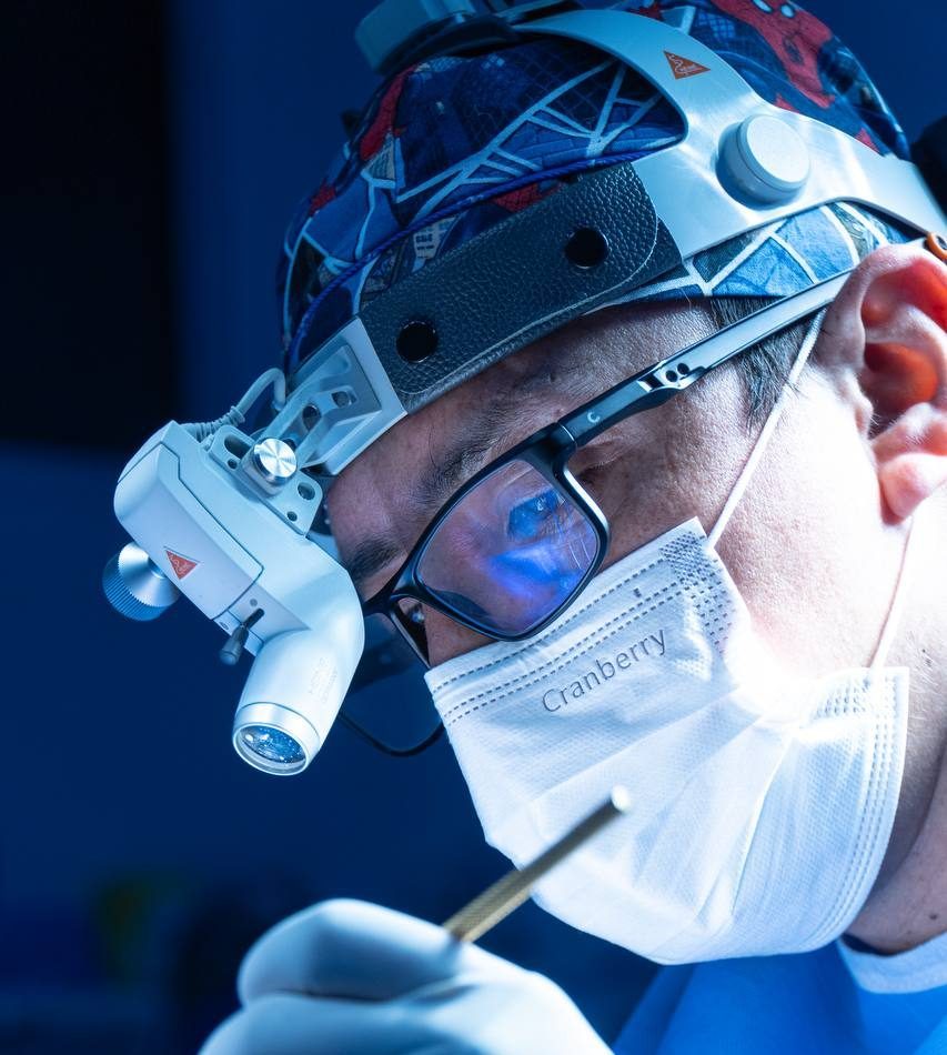 El Dr. Benavides operando con lupas quirúrgicas